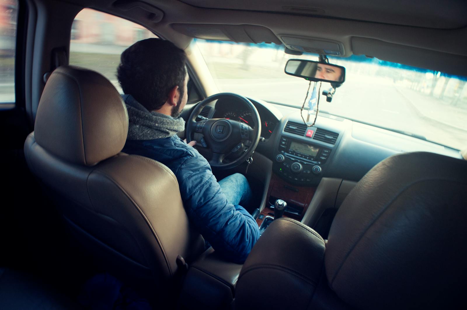 sr-22 A man driving a car with focus on interior, dashboard, and steering wheel, captured from the backseat.